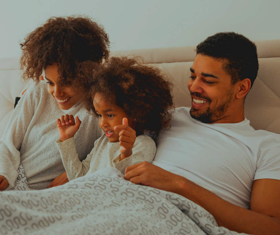 A man and woman lying in bed with a child.