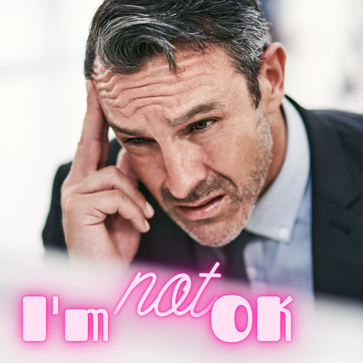A worried man in a suit touches his temple, looking stressed. The neon text overlay reads Im not OK in pink and white letters.